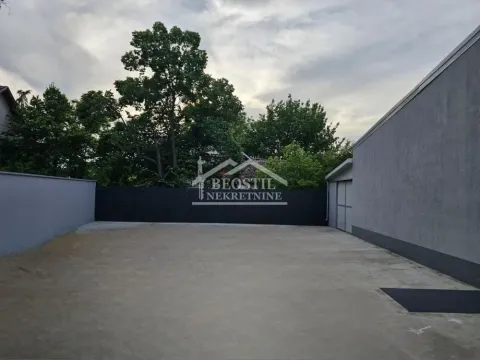 Concrete courtyard with a fence and trees in the background. - image 16