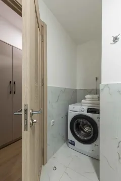 Kupatilo sa veš mašinom i bijelim pločicama sa dezenom mermera. - image 19