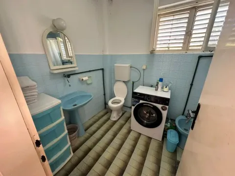 Small bathroom with blue sanitary ware, a washing machine, and a window. - image 3