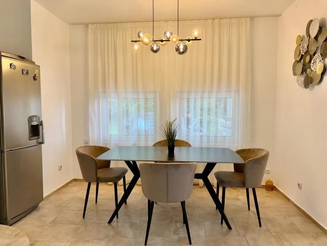 Trpezarija sa stolom, stolicama i modernim lusterom.