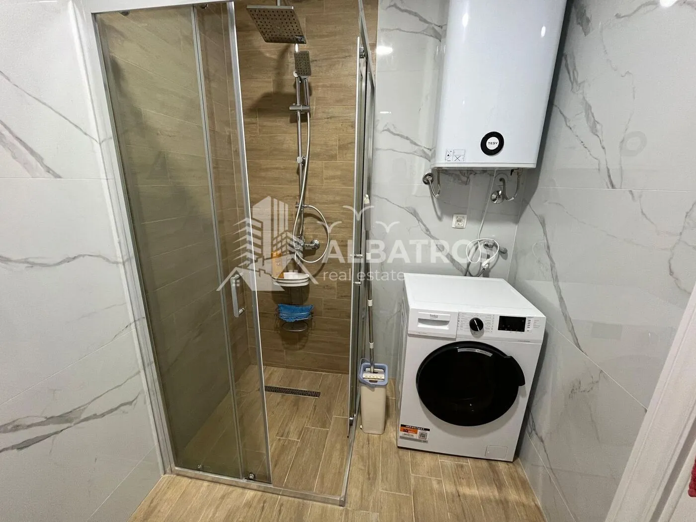 Bathroom with a walk-in shower, water heater, and washing machine.