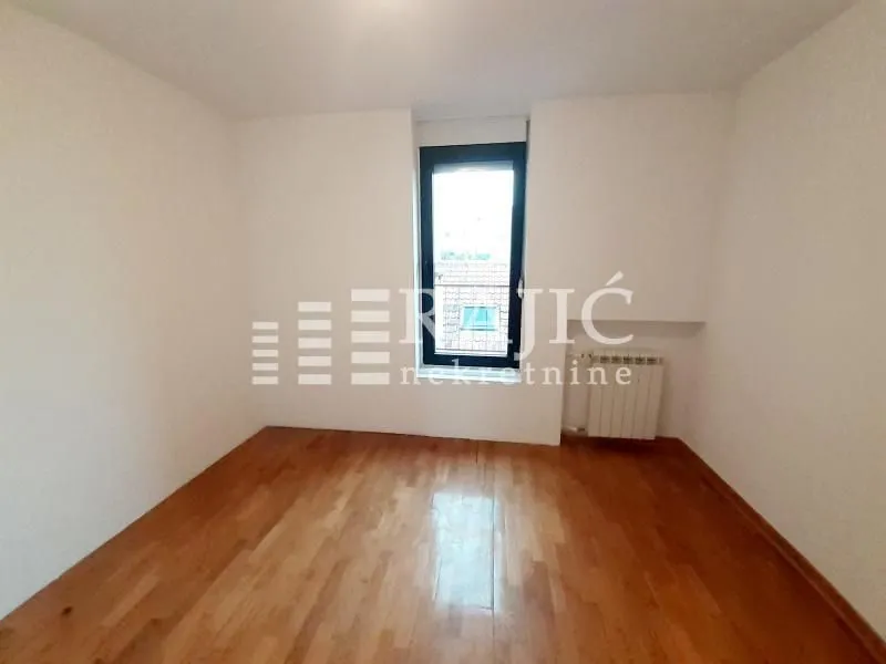 Empty room with wooden flooring and a single window.
