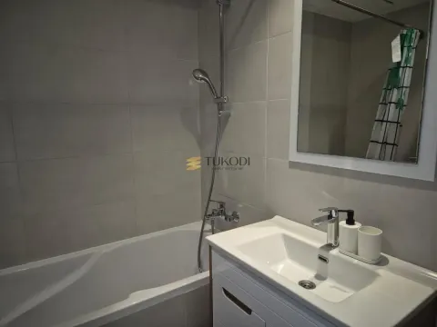 Bathroom equipped with a bathtub, washbasin, and mirror. - image 6