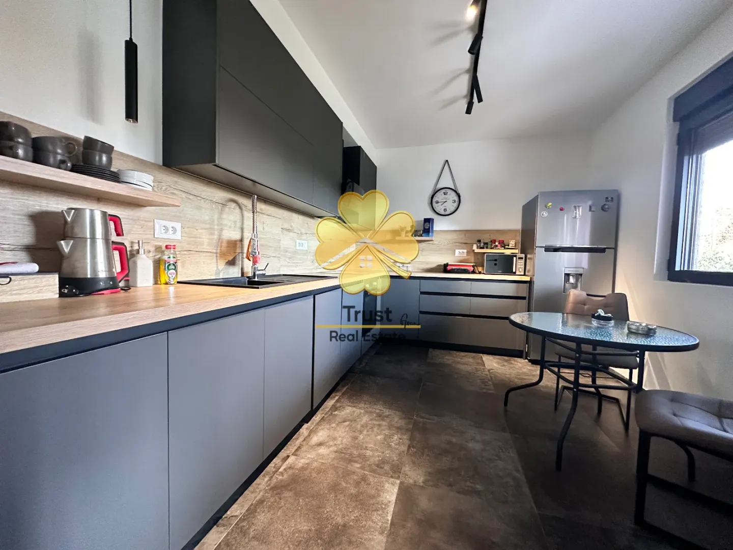 Modern kitchen with dark cabinetry and a dining table.