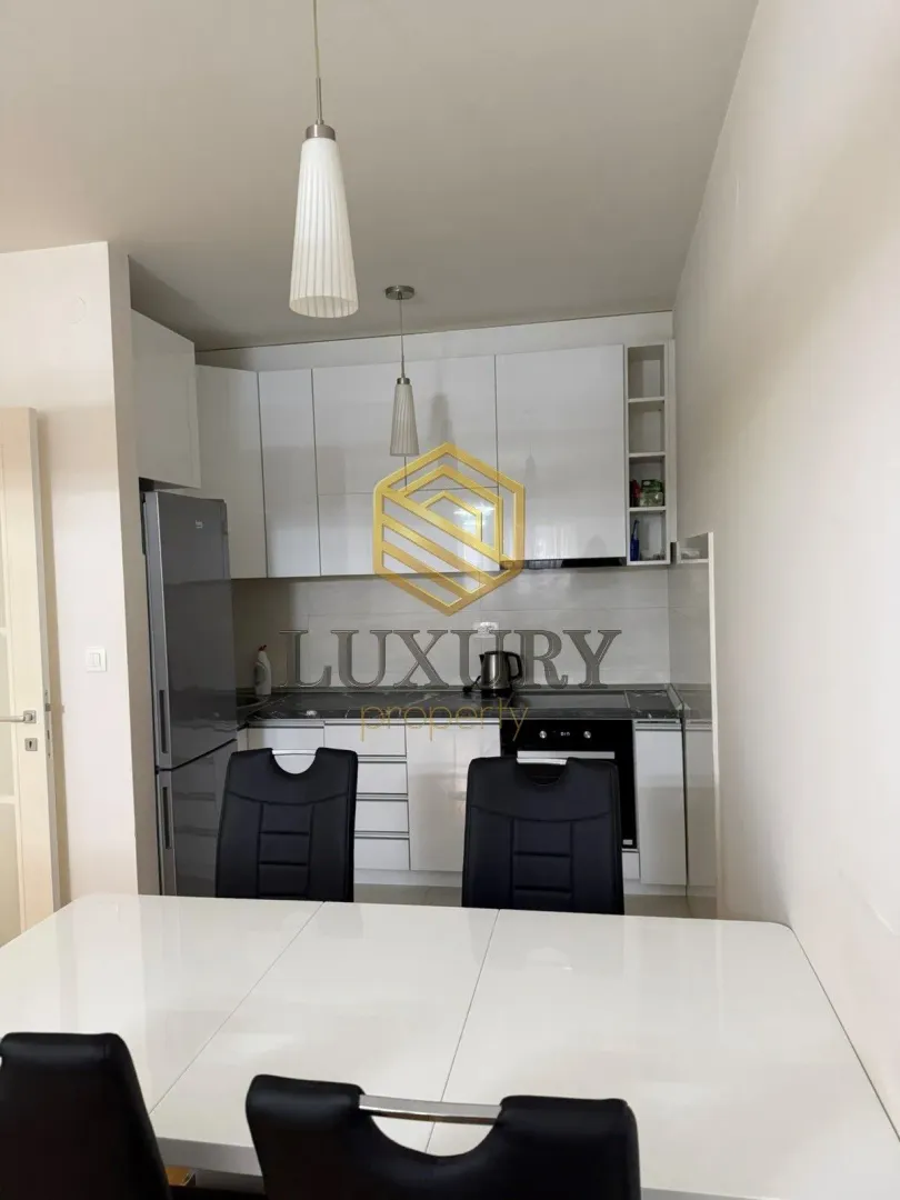 Modern kitchen with white cabinetry and a dining table in the foreground.