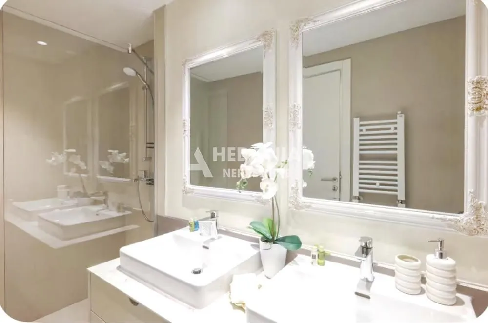 Modern bathroom with two sinks and large mirrors with decorative frames.