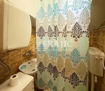 Small bathroom with a sink, toilet, and shower curtain. - image 10