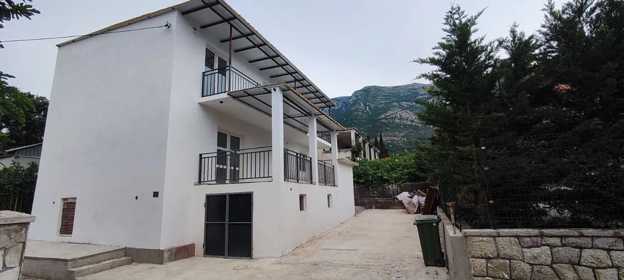 View of the exterior of a white two-story house with terraces and a yard.