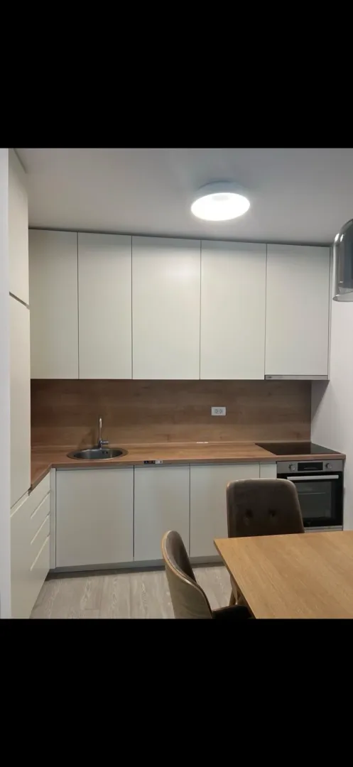 Modern kitchen with white cabinets, wooden countertops, and a dining table.