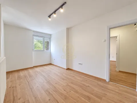 Prazna soba sa drvenim podom, belim zidovima i pogledom kroz prozor. - image 2