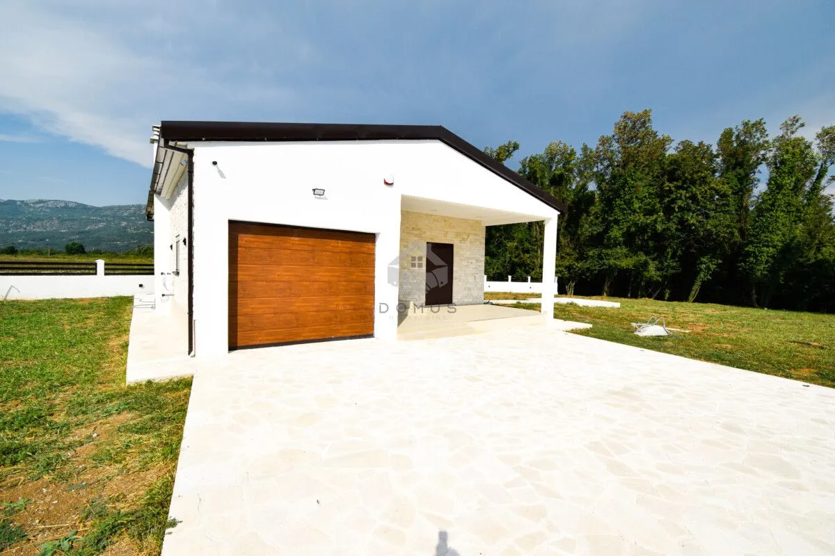 View of the exterior of a ground floor house with a garage and paved yard.