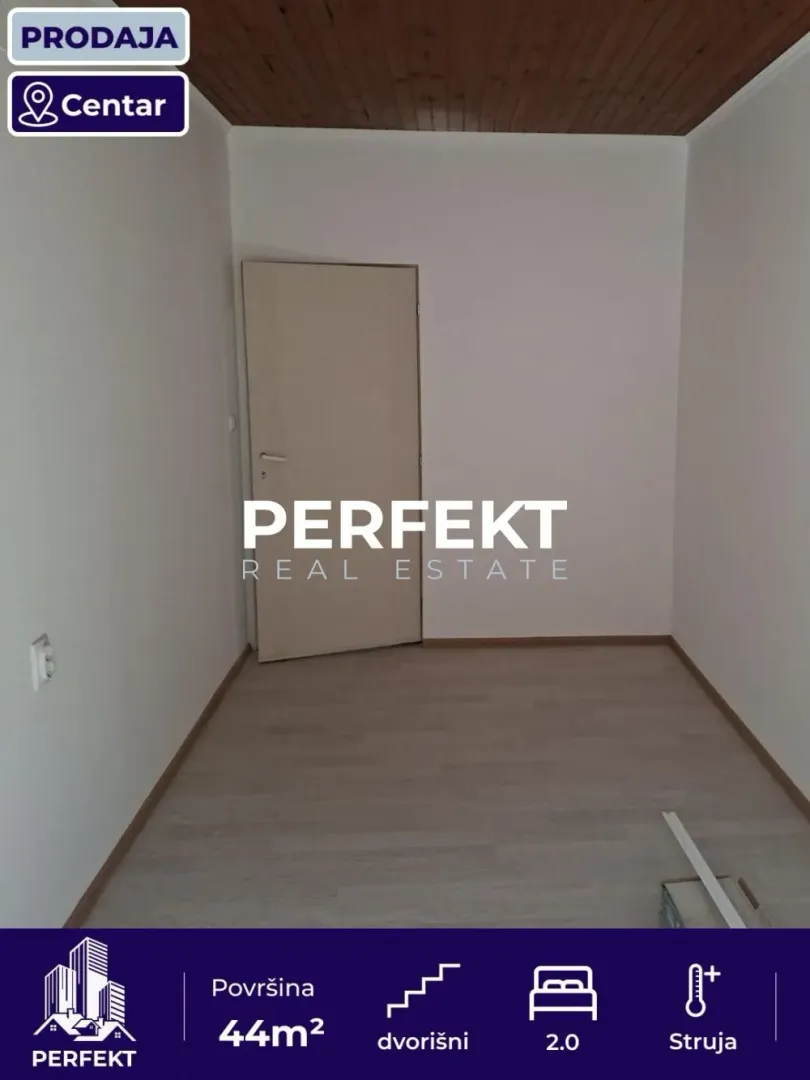Prazna soba sa laminatom i belim zidovima.