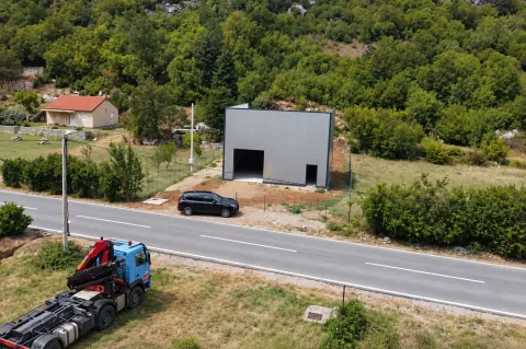 Aerial view of a commercial building next to the road in a green environment. - image 2