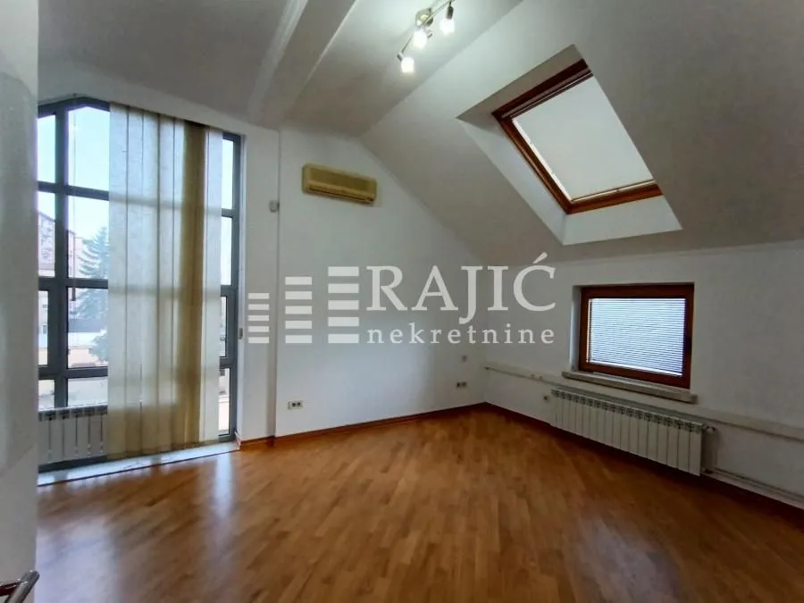 Empty room with hardwood floors and large windows.