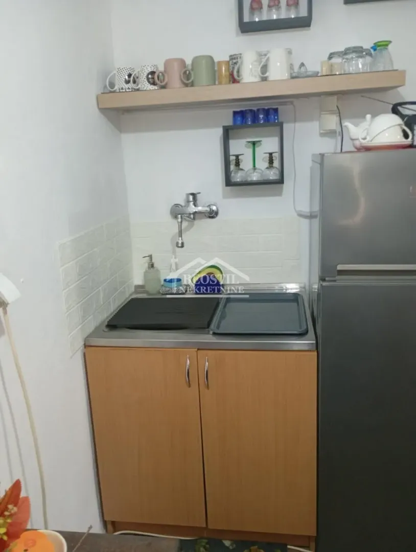 Small kitchen with a sink, cabinetry, and refrigerator.