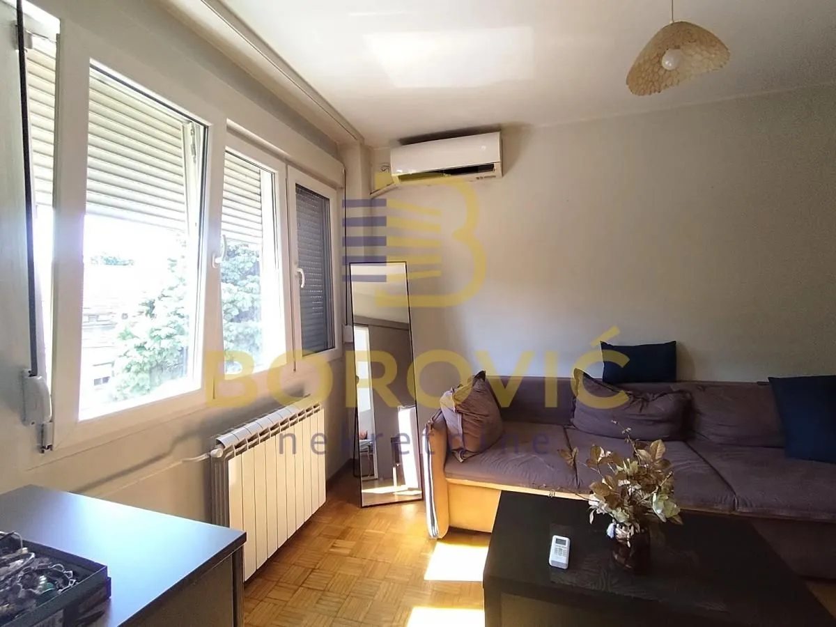 Dnevna soba sa garniturom za sedenje, stočićem i klima uređajem.