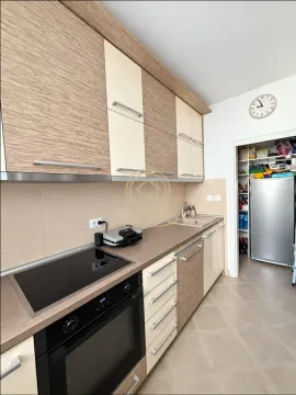 Kitchen with wooden cabinetry, built-in oven and hob. - image 9