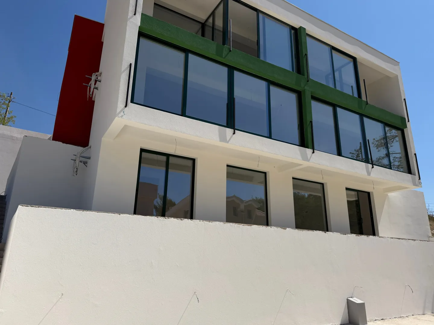 Exterior of a modern residential building with a white facade and large glass surfaces.