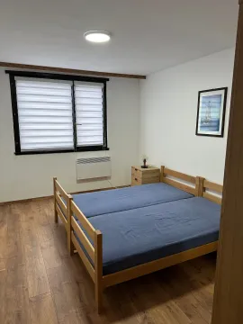 Spavaća soba sa bračnim krevetom, prozorom i drvenim podom. - image 12
