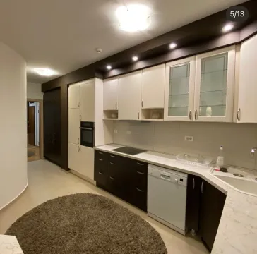 Modern kitchen with white and dark cabinets and a round rug on the floor. - image 5