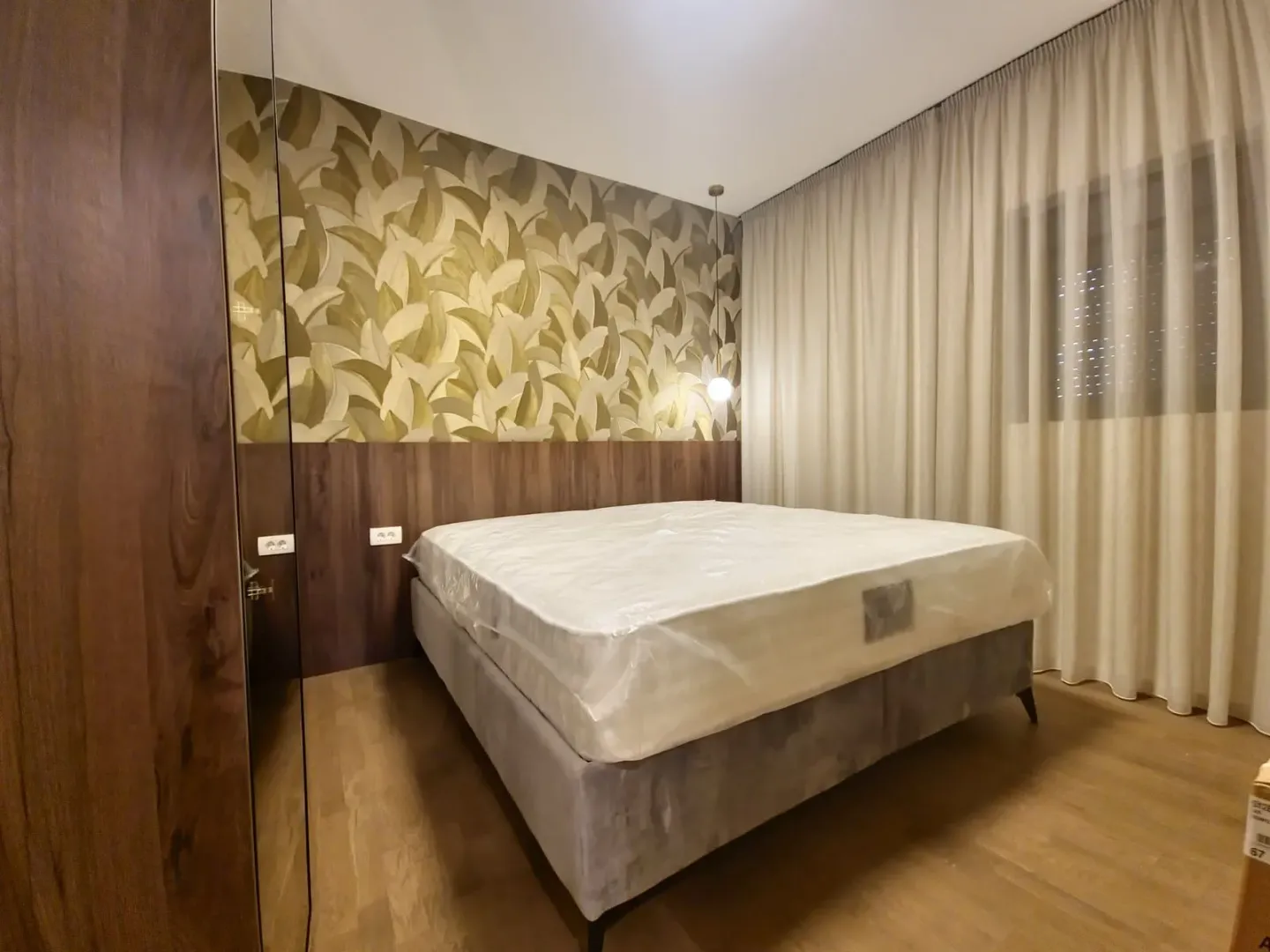 Bedroom with a double bed, wooden wall panels, and wallpaper.