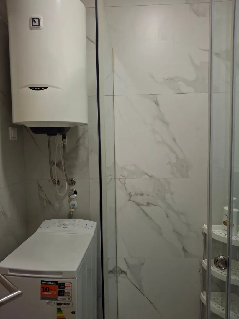 Small bathroom with a shower cabin, water heater, and washing machine.