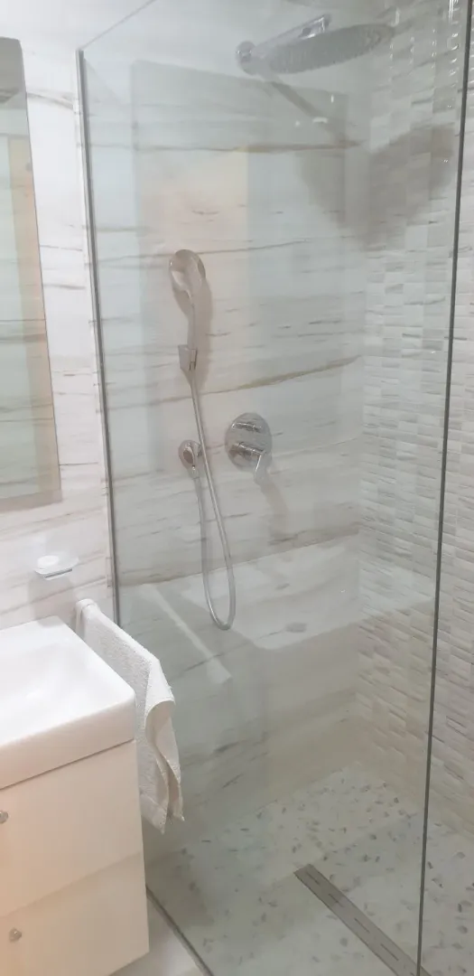 Svijetlo kupatilo sa staklenom tuš kabinom.