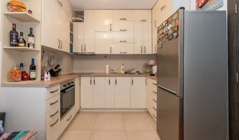 Kuhinja opremljena bijelim elementima, ugradnim uređajima i velikim frižiderom. - image 3