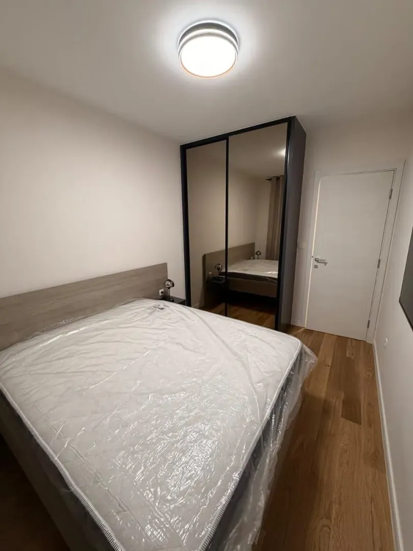 Spavaća soba sa bračnim krevetom i ugradnim ormarom sa ogledalom.