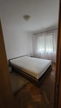 A simply furnished bedroom with a double bed and parquet flooring. - image 11