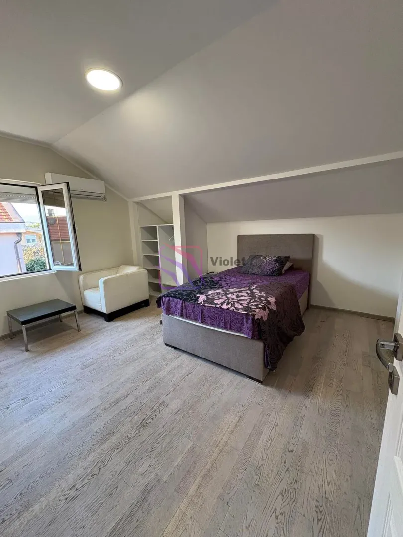 Attic bedroom featuring a double bed, white armchair, and an open wardrobe.