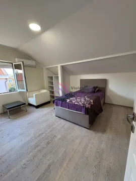Attic bedroom featuring a double bed, white armchair, and an open wardrobe. - image 4
