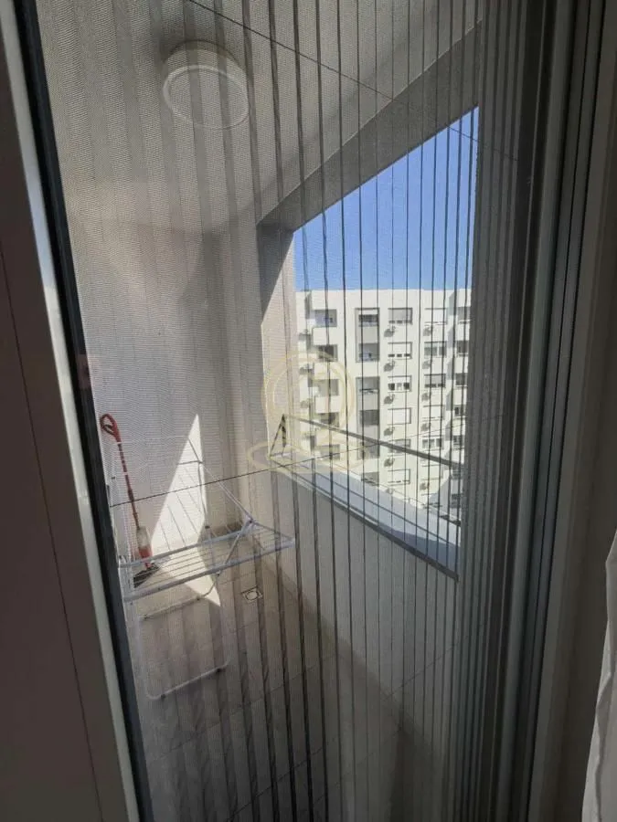 Pogled na natkrivenu terasu kroz balkonska vrata sa mrežicom protiv komaraca.
