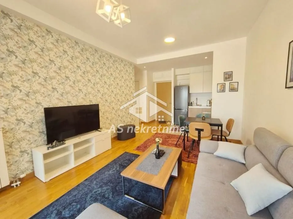 Living room with sofa, TV and dining area in the background.