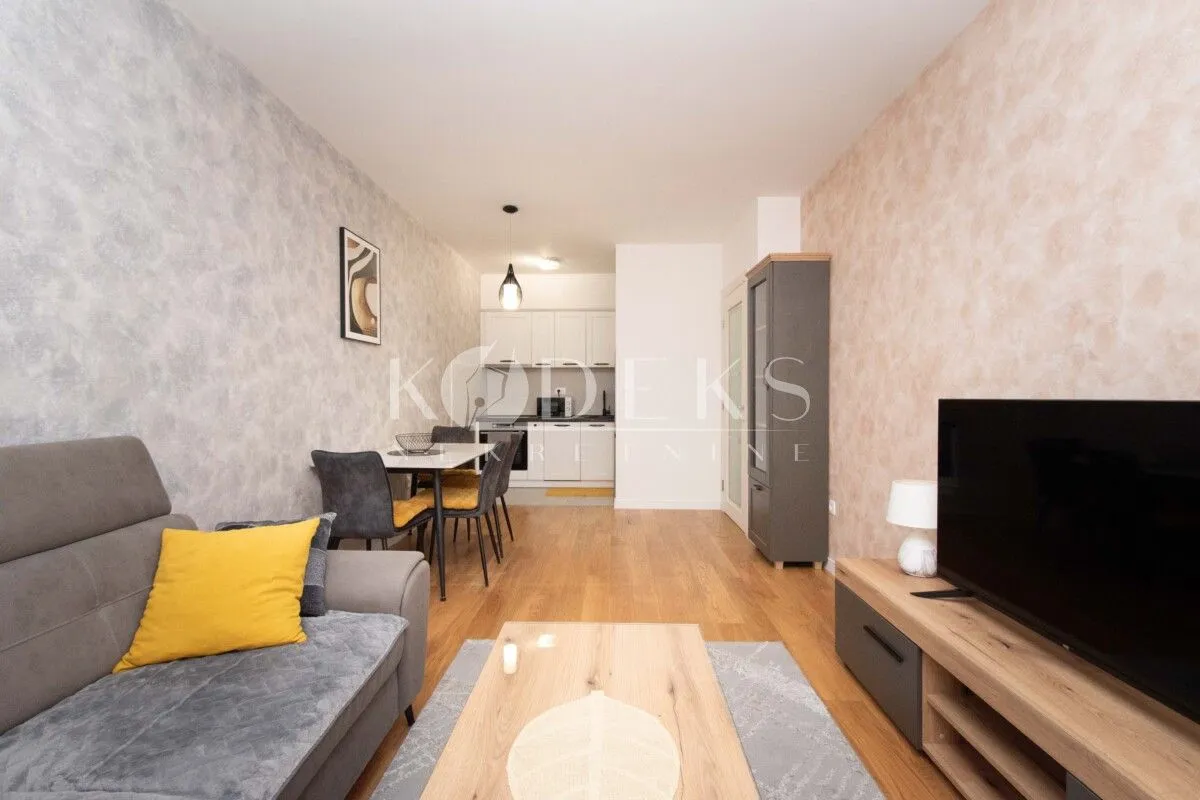 Living room with a sofa, TV, and an adjoining dining area.