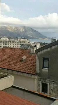 Pogled sa prozora na okolne zgrade i planinu u daljini. - image 6