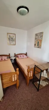 Spavaća soba sa dva drvena kreveta i slikama na zidu. - image 12