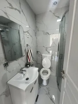 Bright bathroom featuring marble-pattern tiles, a vanity, and a shower. - image 10