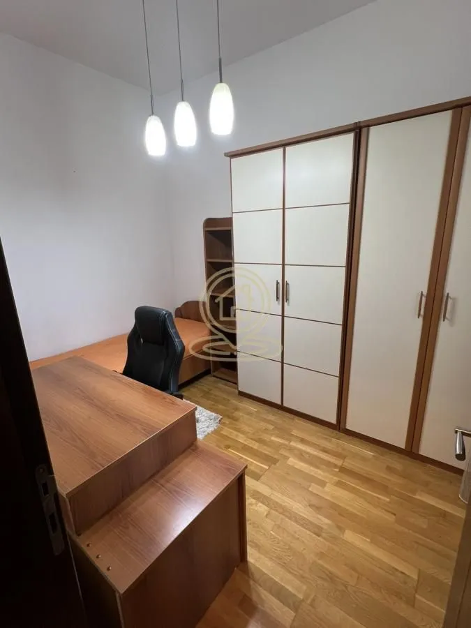 Manja spavaća soba sa krevetom, radnim stolom i velikim garderoberom.