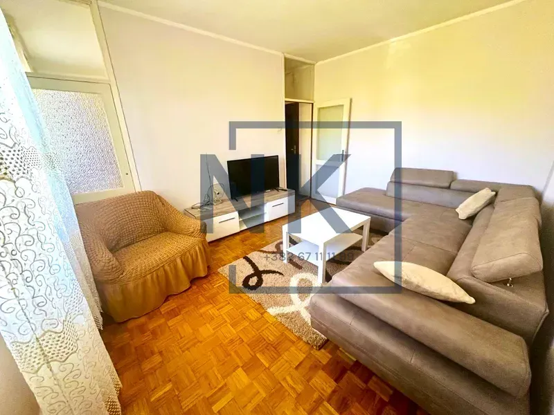 Living room with a sectional sofa, armchair, and TV.