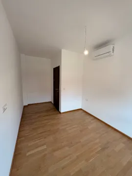 Prazna soba sa bijelim zidovima, parketom i klima uređajem. - image 5