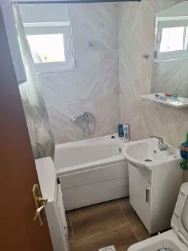 Smaller bathroom with a bathtub, washbasin, and washing machine. - image 6