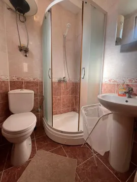 Small bathroom with a shower cabin, toilet, and sink. - image 4