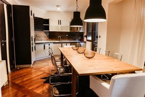 Dining area and modern kitchen with a wooden table.