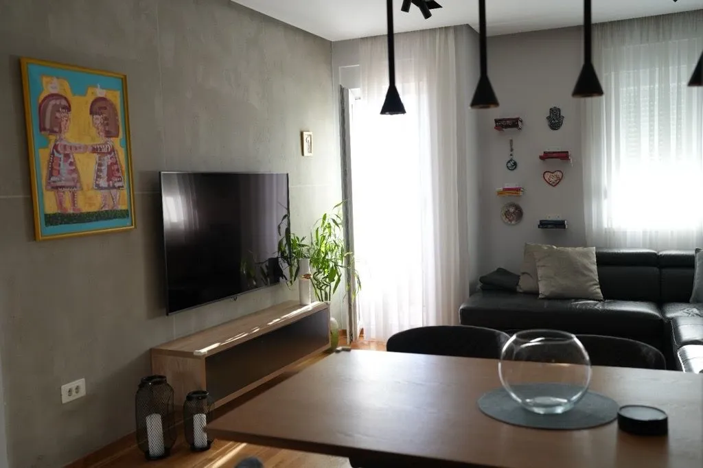 Living room with a sofa, TV, and dining table.