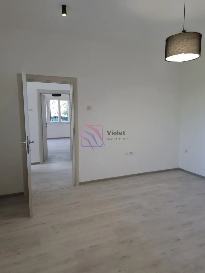 Empty room with laminate flooring and an open door leading to another room.