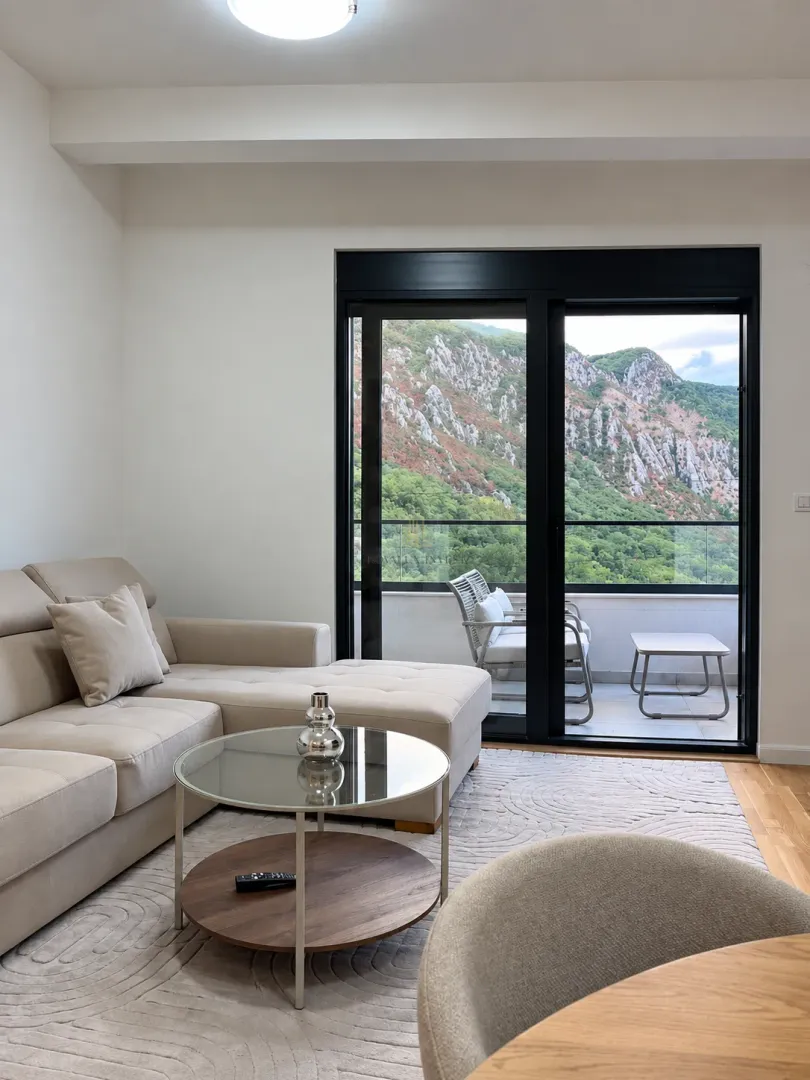 Living room with a sectional sofa, coffee table, and mountain view through the balcony door.