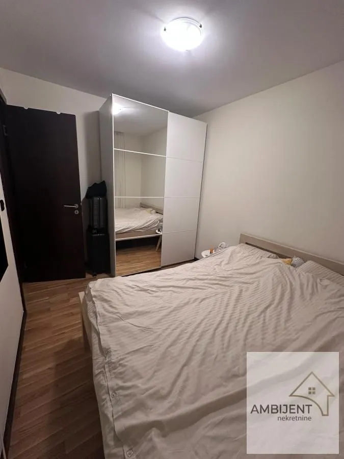 Spavaća soba sa bračnim krevetom i velikim ormanom sa ogledalom.