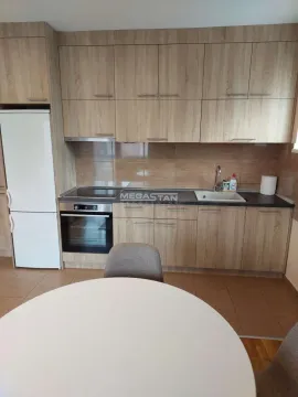 Kuhinja sa drvenim elementima i belim frižiderom, sa okruglim stolom u prvom planu. - image 9