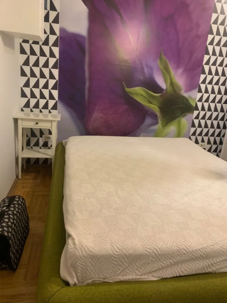 Bedroom with a double bed and decorative wallpaper on the wall.